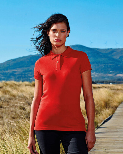 A stack of colorful Asquith and Fox ladies' polycotton blend polos, model AQ025.
