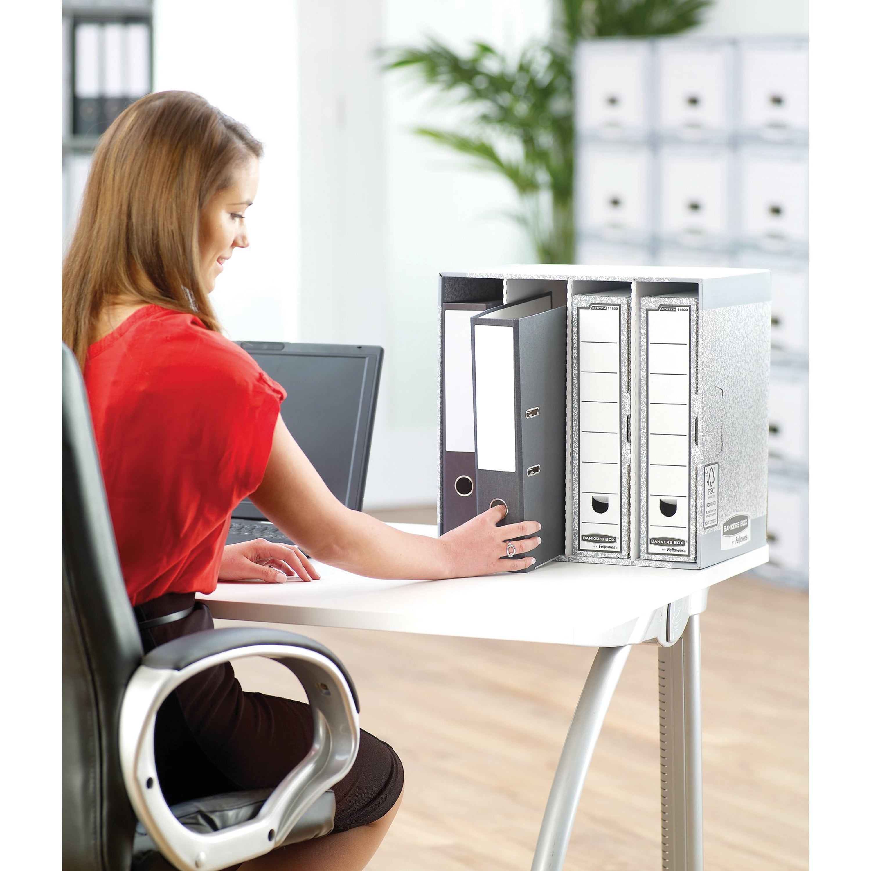 The grey Bankers Box System Stax File Store shown in a typical office setting beside a desk.