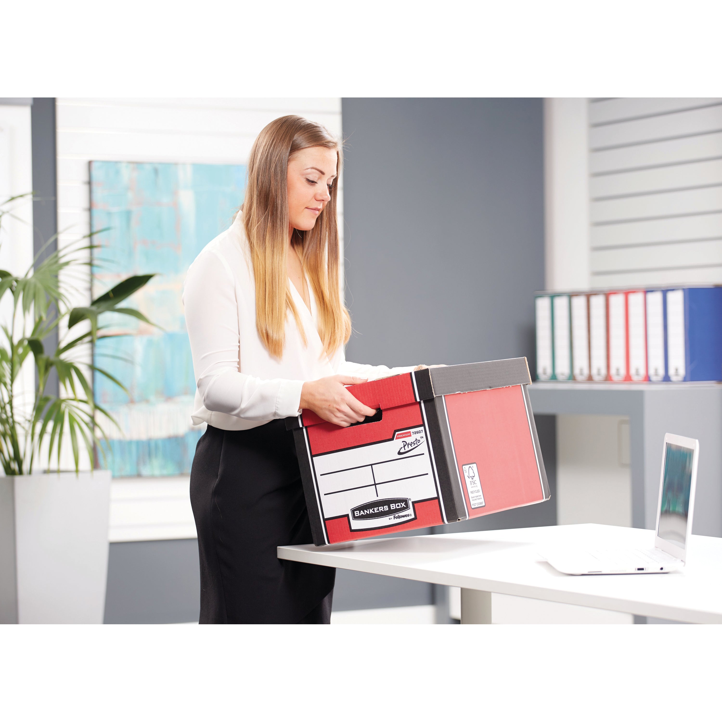 A person securely placing the lid on the tall red Bankers Box Premium storage container.