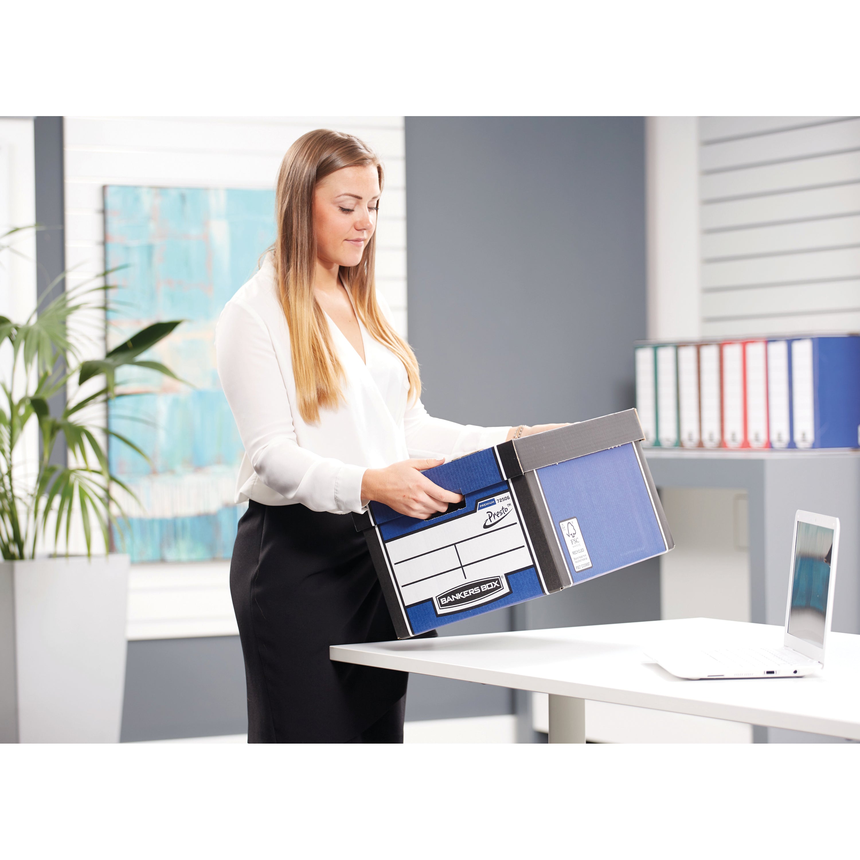 A person placing the lid on the blue Bankers Box Premium Classic box for secure closure.