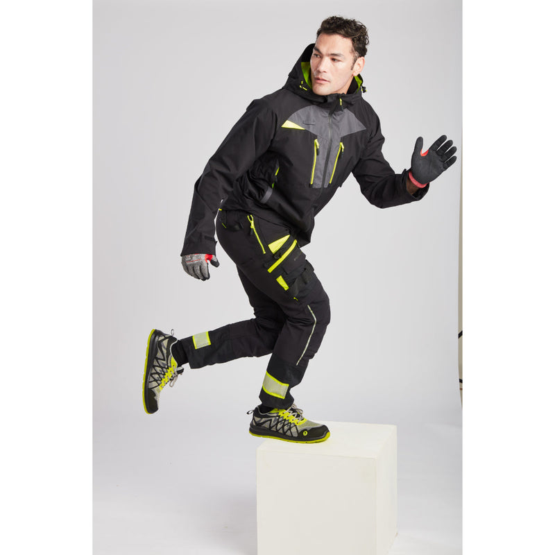 Man in black Portwest DX4 shell jacket and work trousers captured from a lower angle.