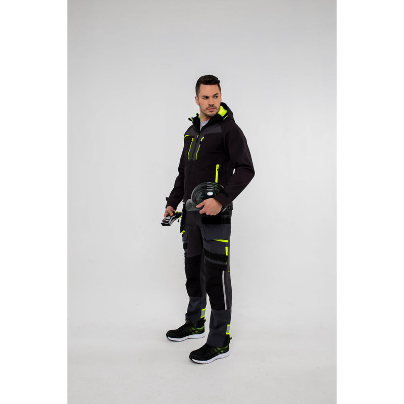 Man in Portwest DX4 Softshell 3L jacket and work trousers standing confidently.