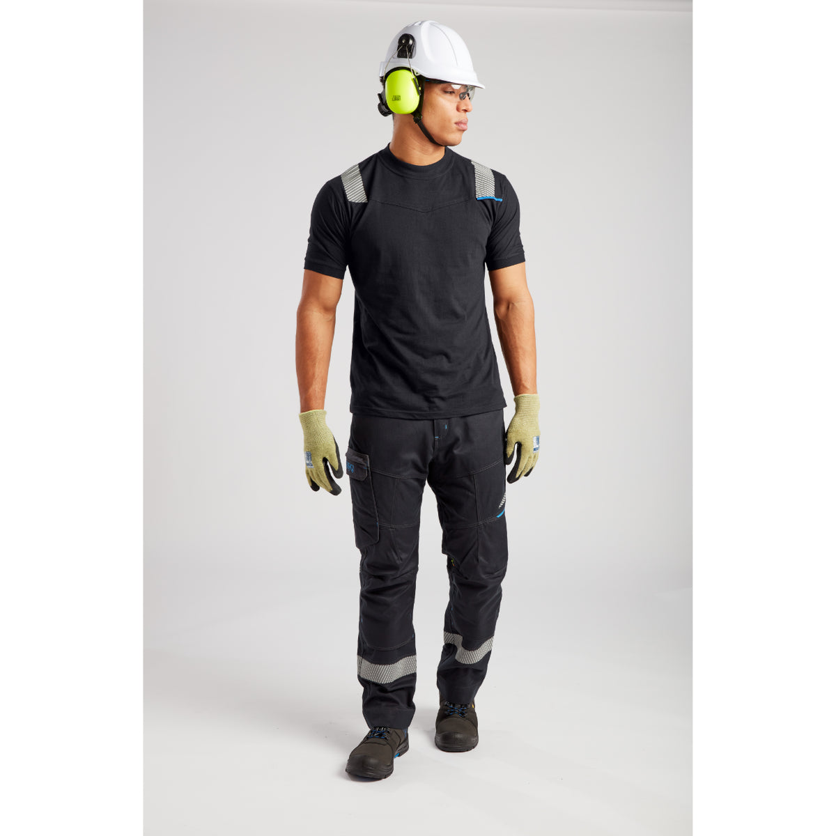 Worker in protective gear with white helmet, yellow earmuffs, black T-shirt and reinforced work pants