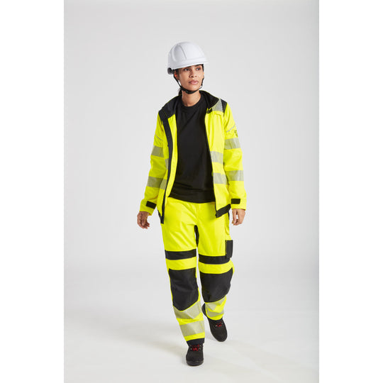 Female construction worker in bright yellow reflective jacket and pants with white helmet and safety shoes