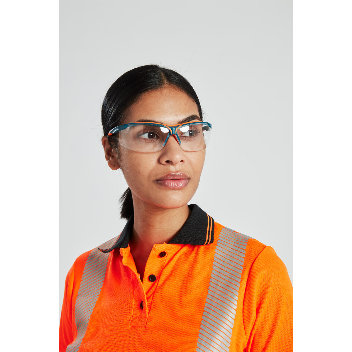 Woman wearing safety glasses and hi-vis orange polo shirt with reflective stripes