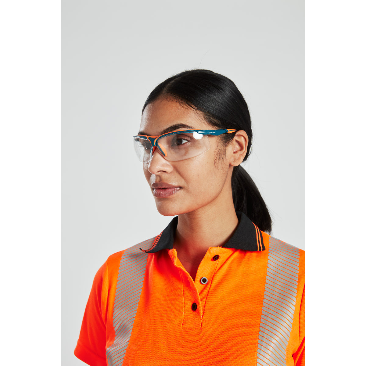 Side view of woman in hi-vis orange polo shirt and safety glasses with black collar