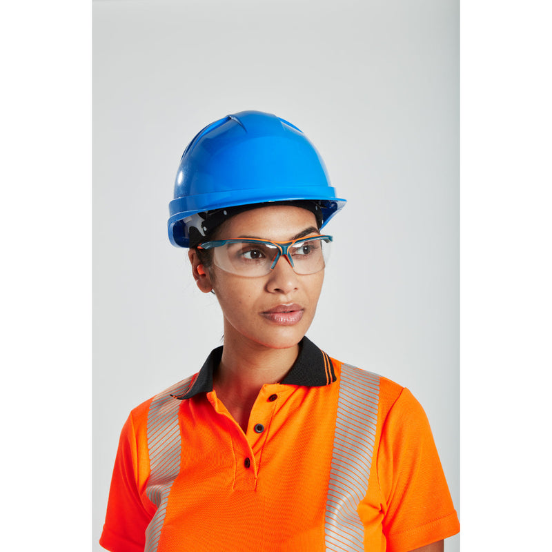 Woman in hi-vis orange polo shirt with blue hard hat and safety glasses looking ahead