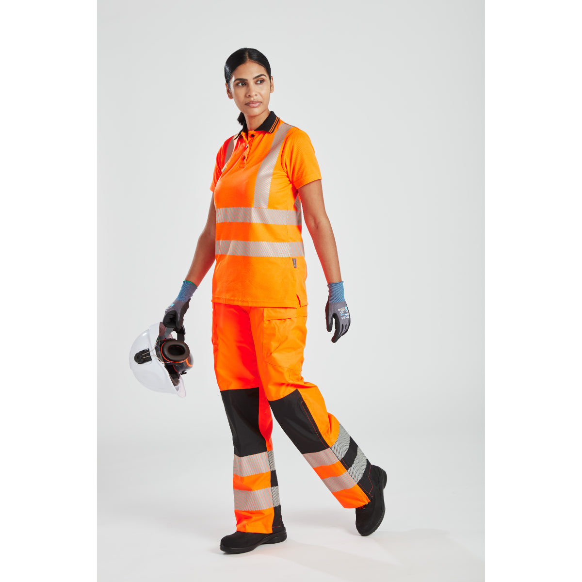 Model wearing Portwest hi-vis women's rain trousers, jacket, and hard hat.
