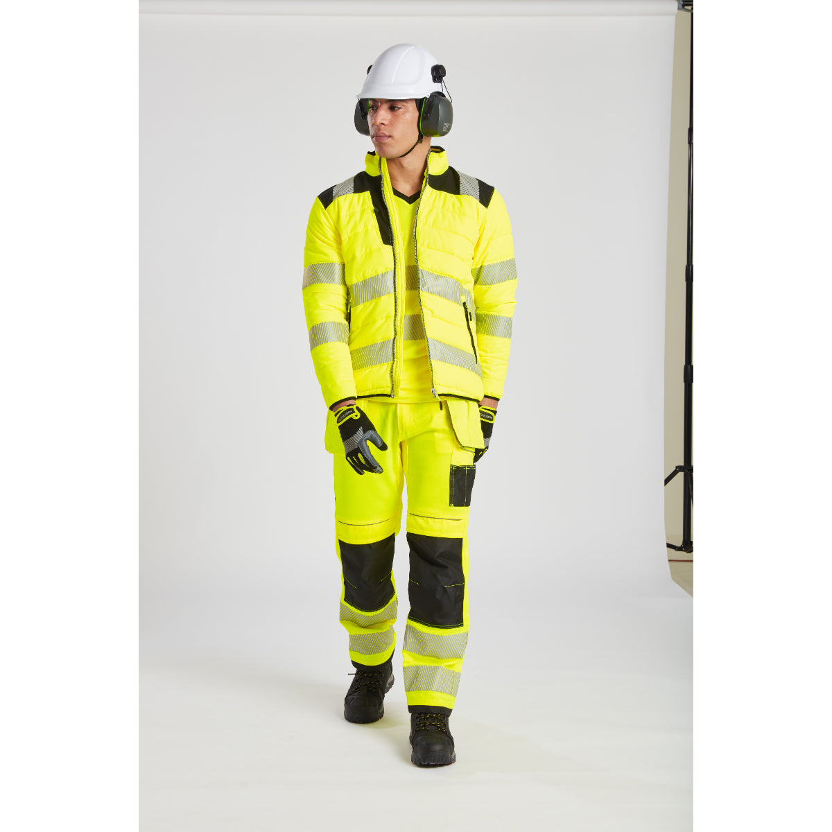 Model in yellow Portwest PW3 Baffle Jacket with safety helmet and glasses.