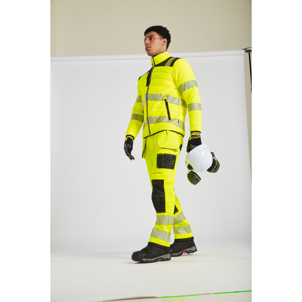 Back view of a model in a yellow Portwest PW3 Baffle Jacket with a safety helmet.