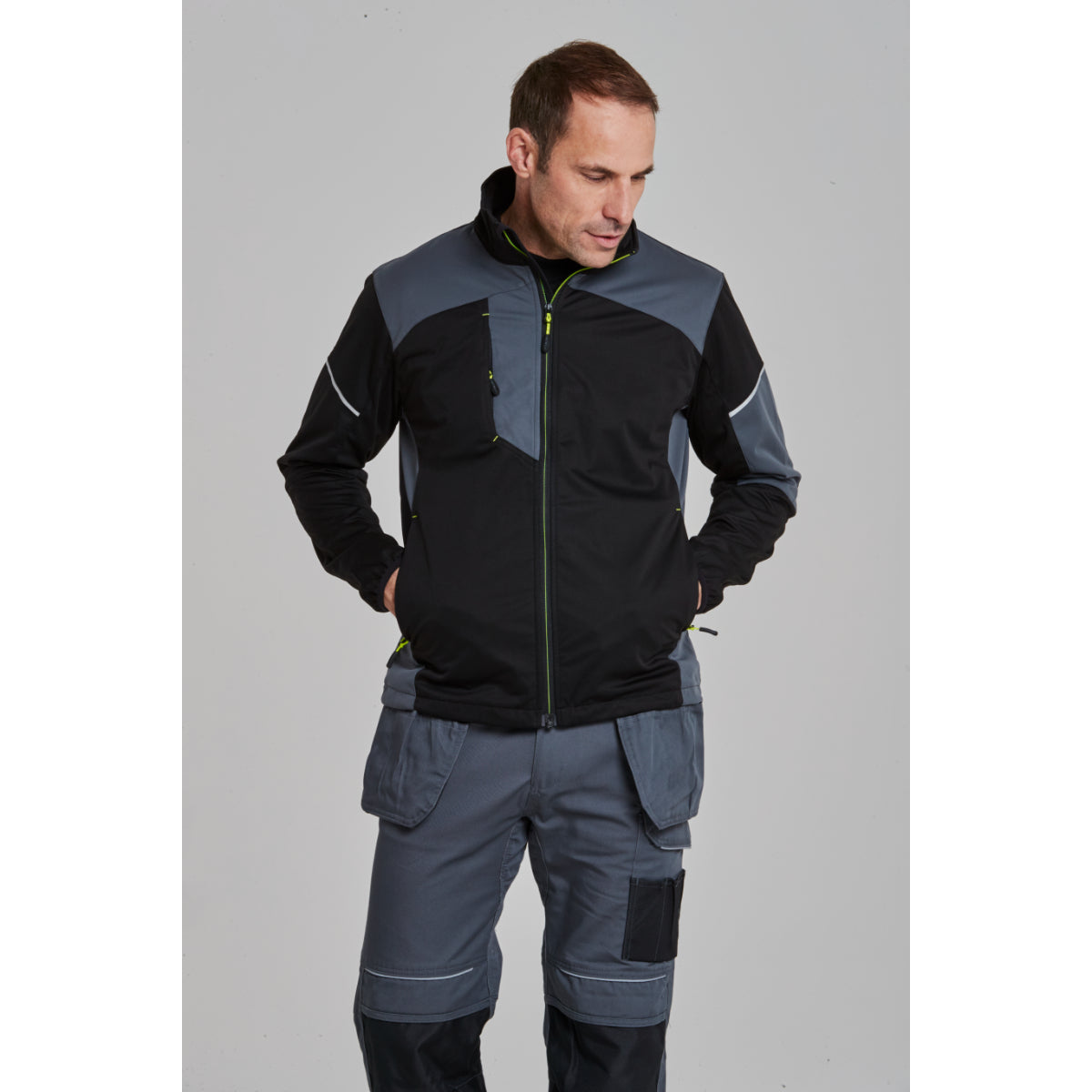 A worker wearing the Portwest Flex Shell Jacket at a worksite.
