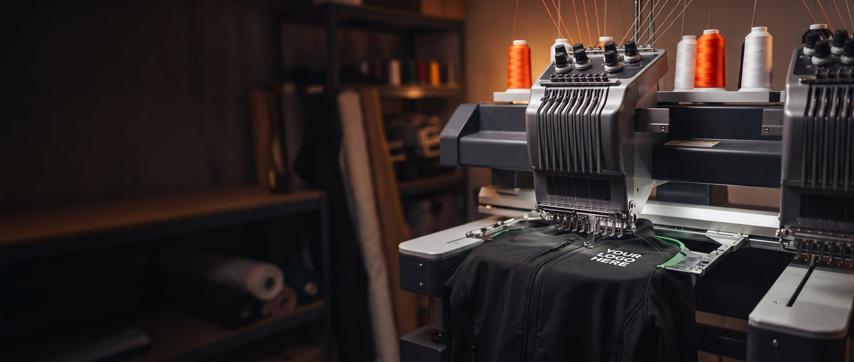 Embroidery machine stitching a logo onto a black softshell jacket