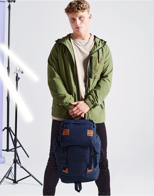 Angled view of the navy and tan Bagbase Urban Explorer Backpack, highlighting its heritage styling.