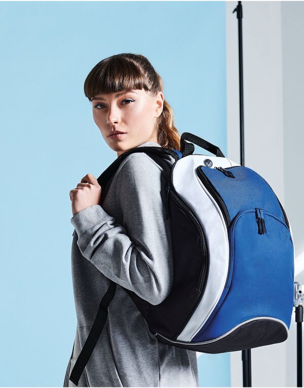 A collection of Bagbase Teamwear Backpacks in various team colors like red, blue, green, and black.