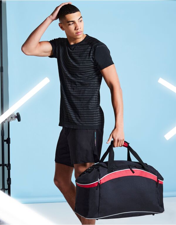 A variety of Bagbase Teamwear Holdalls shown in different colors like red, royal blue, and navy.