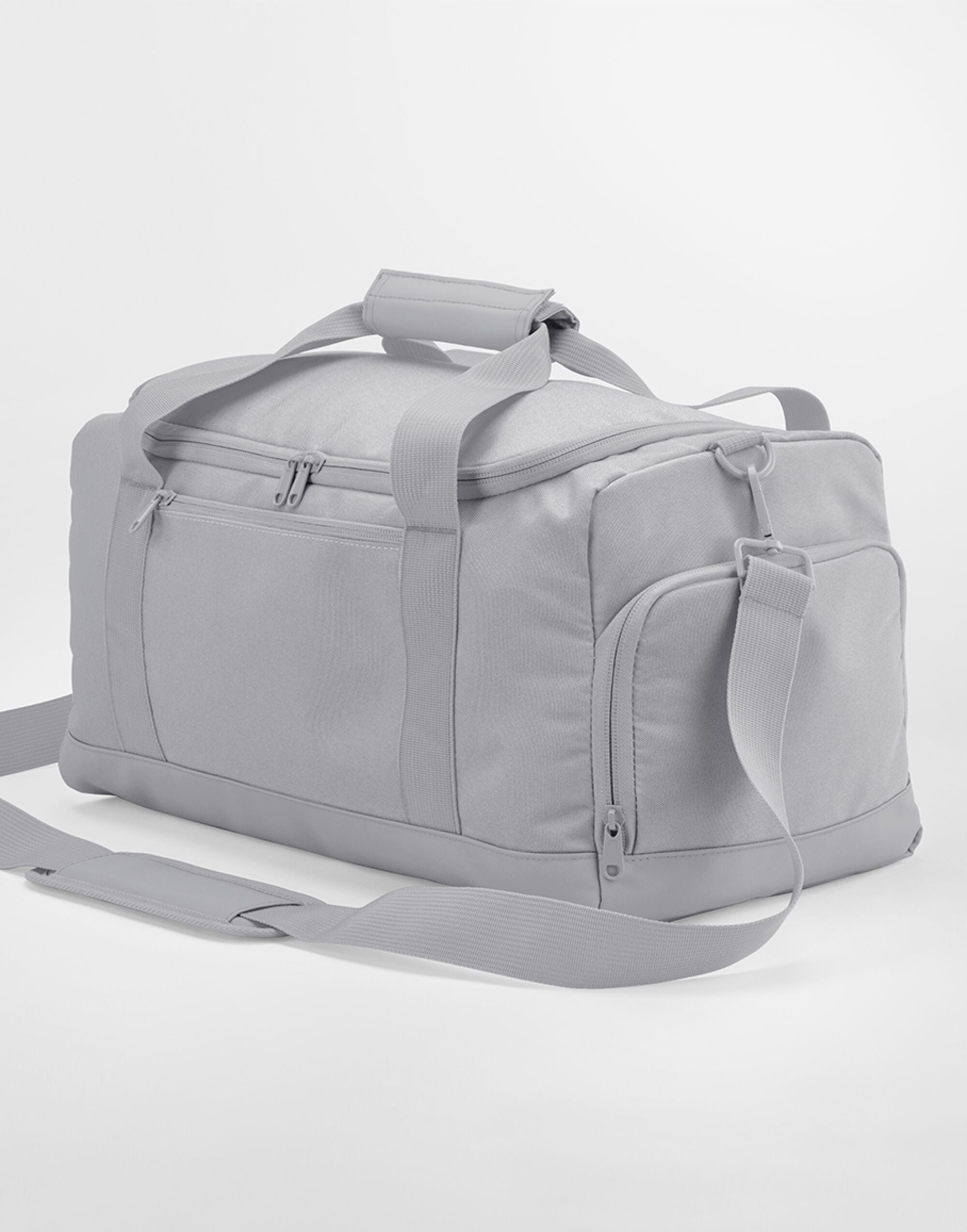 A person carrying the classic red Bagbase Small Training Holdall to show its compact and portable size.