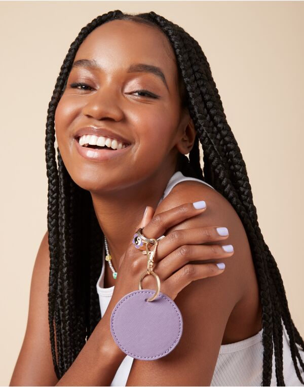 Angled view of the soft pink Bagbase Boutique Circular Key Clip, highlighting its round shape.