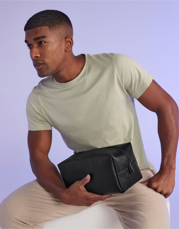 Angled view of the soft pink Bagbase Boutique Toiletry Case, highlighting its structured, spacious design.