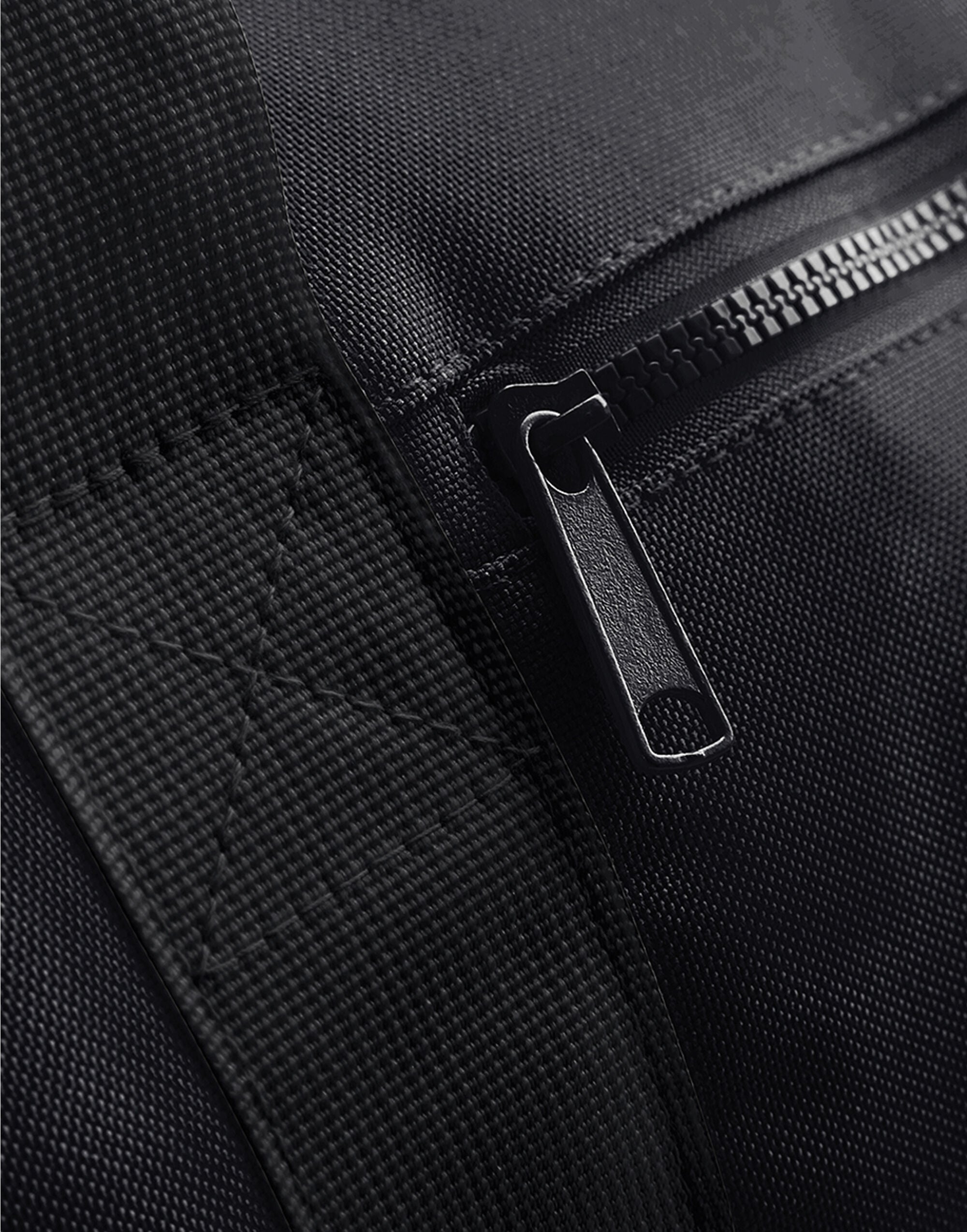 Side profile of the black mini essential backpack.