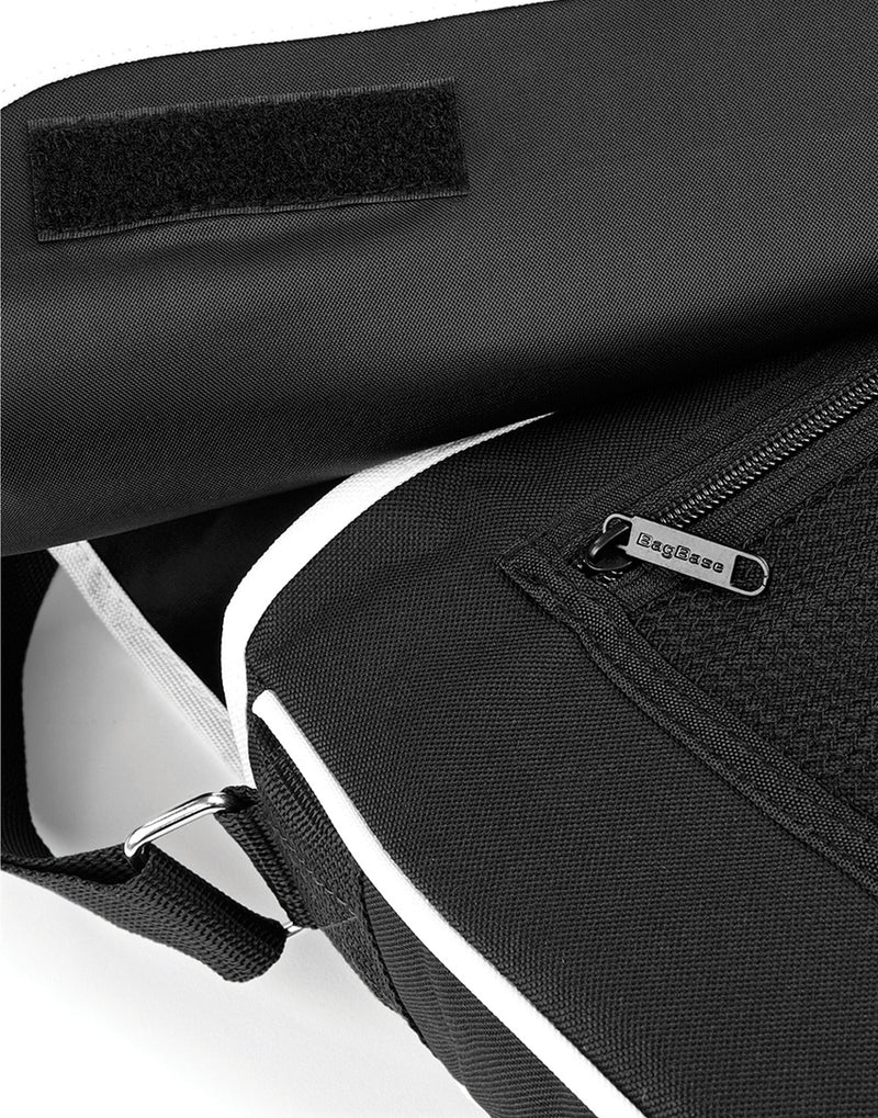 Side profile of the black Bagbase Retro Messenger, illustrating its capacity for books and a small laptop.