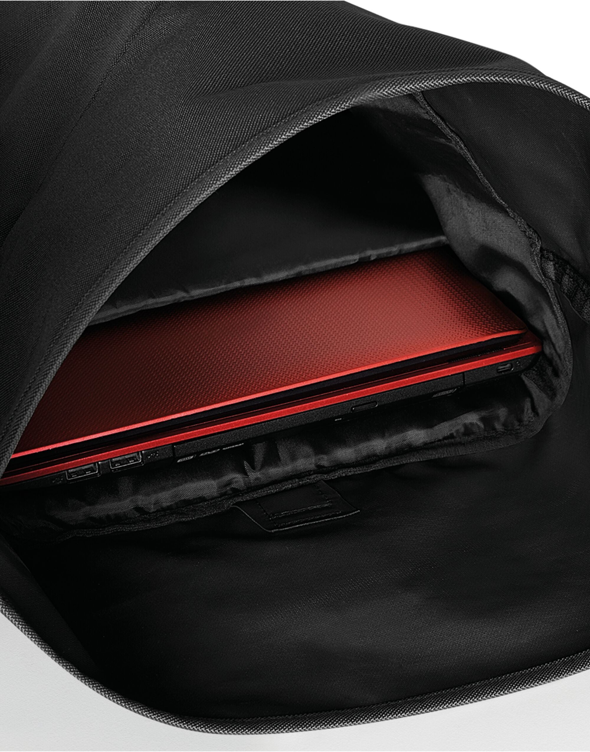 Side profile of the black Bagbase Roll-Top Backpack, illustrating its slim profile when rolled down.