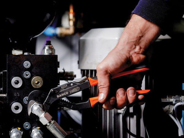 The Bahco Ergo slip joint pliers shown in use, gripping a round pipe.